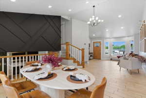 Open concept living area featuring a decorative dark accent wall, light tile flooring, and a natural wood entry door with glass inserts