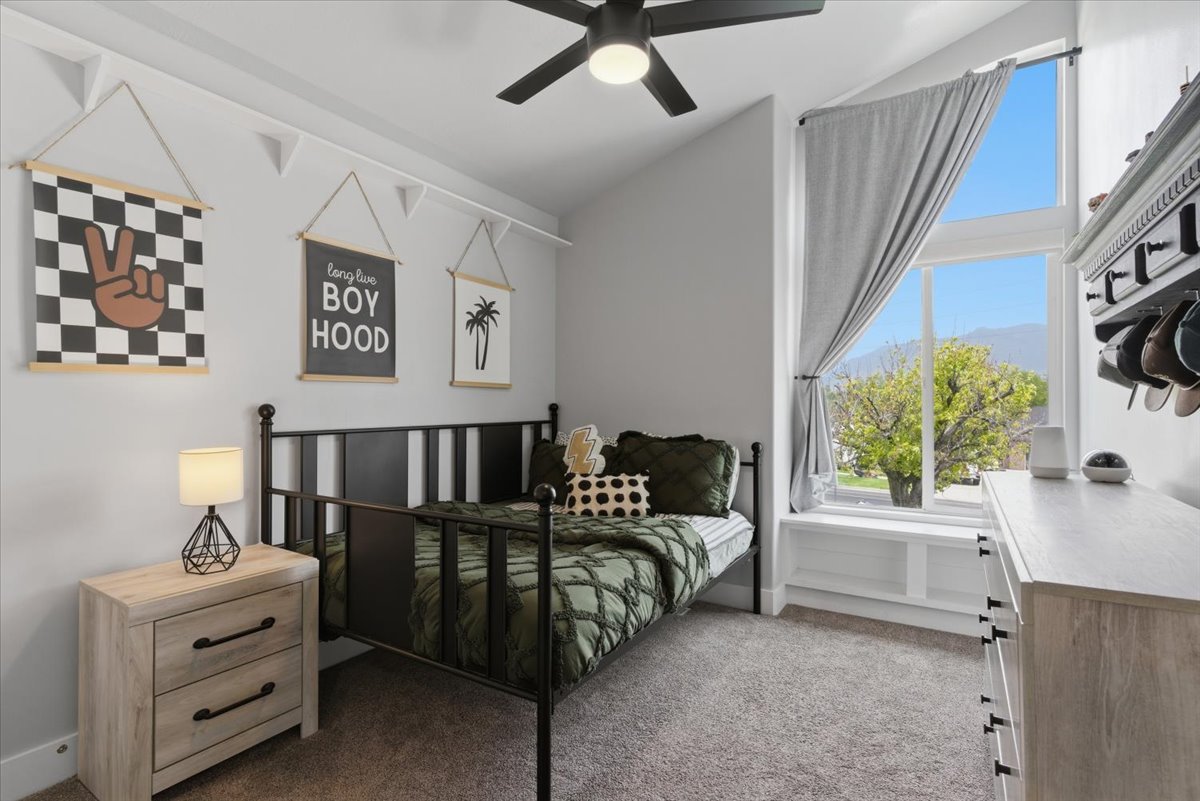 Bedroom with vaulted ceiling with a black ceiling fan