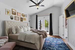 Vaulted ceiling room with hardwood-finish flooring, a ceiling fan, and French doors leading out to a private deck