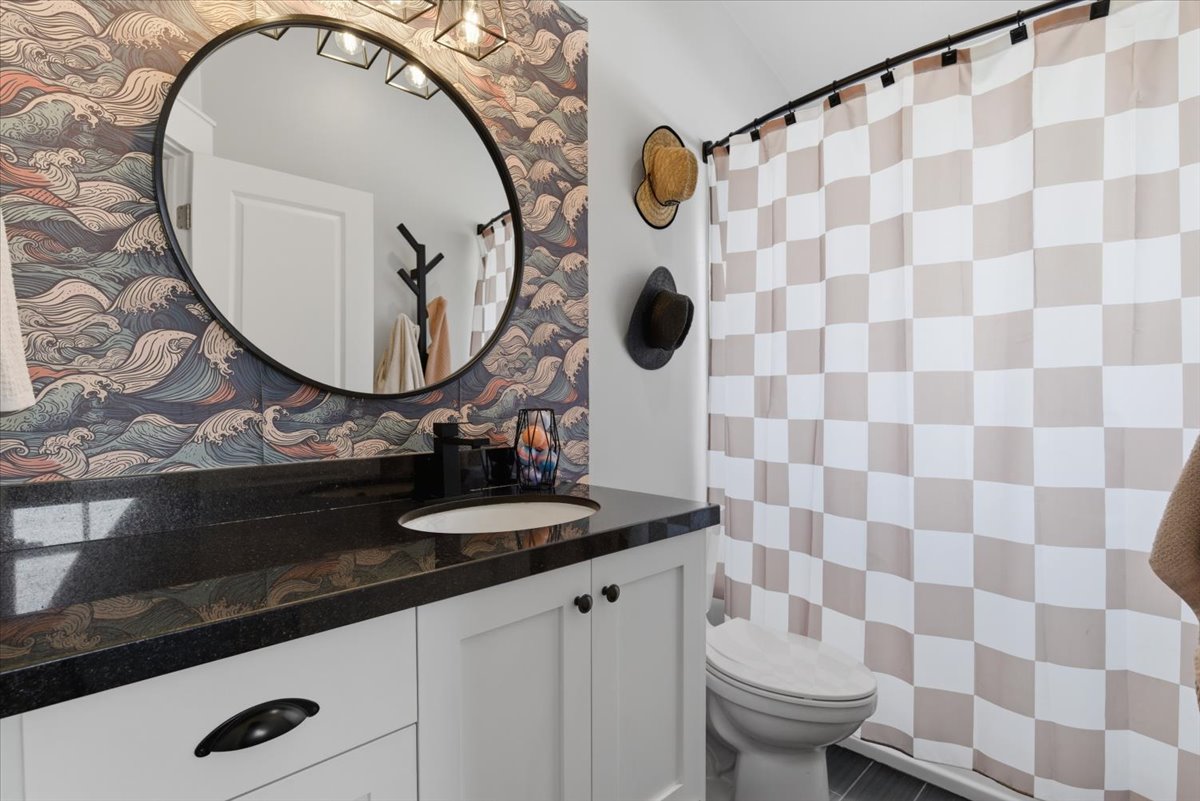 Bathroom featuring a white vanity with black hardware and a black granite countertop