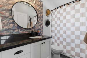 Bathroom featuring a white vanity with black hardware and a black granite countertop