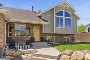 Stone facade with vertical siding accents, featuring a prominent arched window and a natural wood-finish entry door