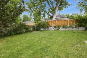 Spacious grassy yard with mature trees and a wood privacy fence