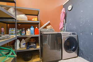 Dedicated laundry area featuring a front-load washing machine and a top-load washing machine, accompanied by ample built-in shelving for storage