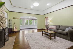 Spacious living area featuring wood-finish flooring, a stone-clad fireplace, and a decorative ceiling light fixture