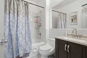 Bathroom featuring a white subway tile surround, a built-in bathtub with shower, a dark wood-finish vanity with a light countertop, and a large wall-mounted mirror