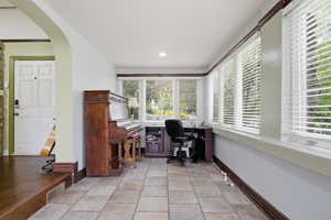 Versatile room featuring tile flooring, a built-in window desk, recessed lighting, and multiple windows with blinds