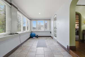 Sunroom with extensive window line, tile flooring, recessed lighting, and arched French doors