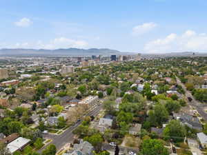 Urban landscape featuring a cityscape with high-rise buildings, residential neighborhoods, tree-lined streets, and distant mountains