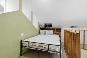 Loft space featuring a sloped ceiling and light green accent wall