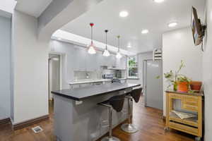 Kitchen featuring an eat-in island with dark countertops, recessed lighting, and wood-finish flooring