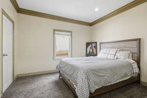 Neutral-toned bedroom featuring crown molding, recessed lighting, and soft carpet flooring