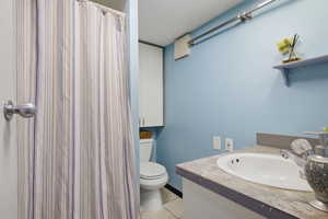 Bathroom featuring light blue walls, built-in shelving, white vanity with integrated sink, and white overhead cabinetry