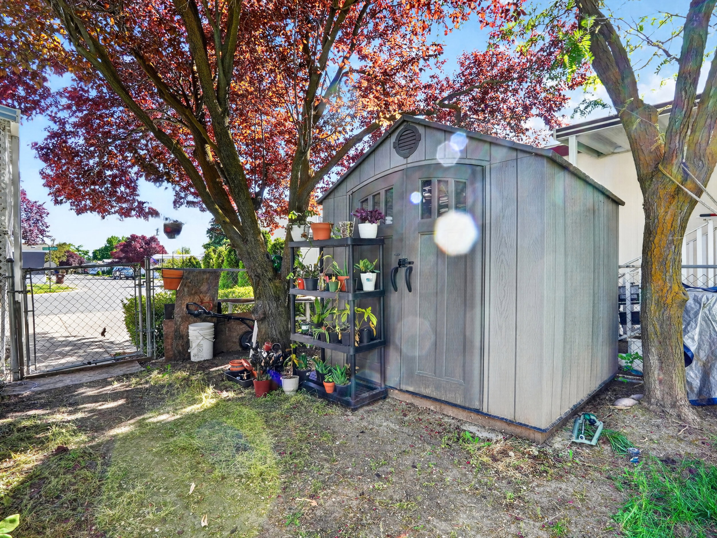 Freestanding storage shed with wood-look siding and arched double doors