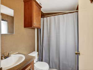 Bathroom with a built-in wood-finish vanity, a matching wood-finish wall cabinet, and a shower area with a metal shower rod
