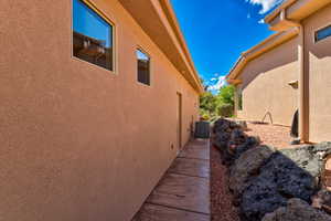 Stucco exterior with multiple windows, concrete walkway, and a rock wall feature with red gravel