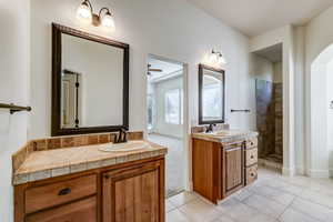 Dual wood-finish vanities featuring tile countertops and integrated sinks