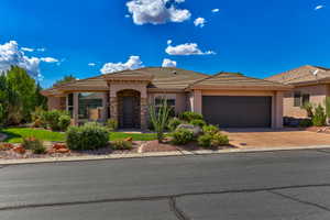 Desert contemporary exterior featuring a neutral stucco finish, stone accents, and a tile roof