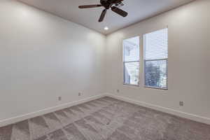 Neutral-toned room featuring a ceiling fan, recessed lighting, two windows with blinds, and geometric pattern carpeting