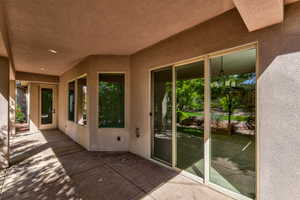 Covered concrete patio with recessed lighting, offering multiple access points to the interior