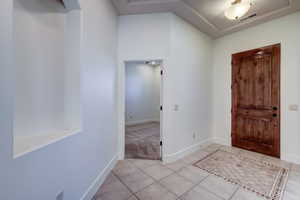 Entryway featuring tile flooring with decorative inlay, a solid wood door, and a recessed wall niche