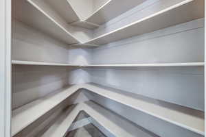 Corner pantry featuring multiple levels of built-in shelving