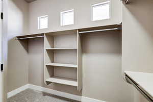 Walk-in closet featuring built-in shelving, hanging rods, and three transom windows