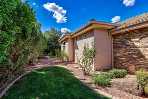 Landscaped exterior featuring stucco siding and a stone accent wall