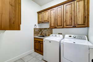 Functional laundry area featuring extensive wood cabinetry, a utility sink, and tile flooring