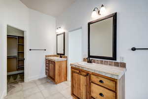 Dual vanity with wood-finish cabinetry, tile countertops, and integrated sinks
