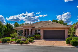 Southwestern-style residence featuring a stucco exterior, a tiled roof, a two-car garage, and desert-inspired landscaping