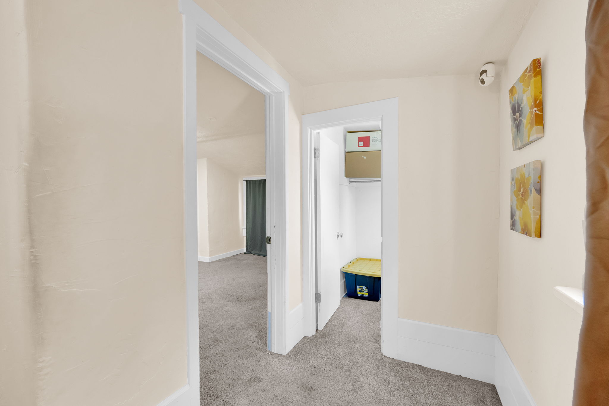Hallway with neutral wall tones, white trim, and gray carpeted flooring