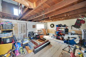 Exposed wooden ceiling beams spanning across the space, with natural light entering through two windows