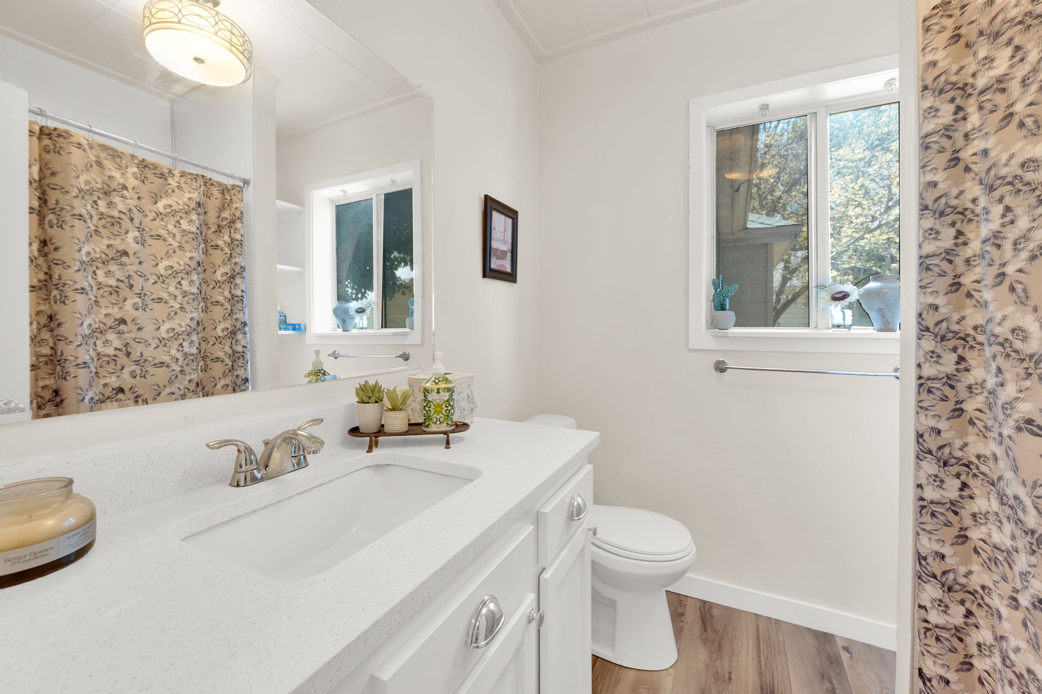 Bathroom featuring a white vanity with an integrated sink, chrome faucet, and spacious mirror
