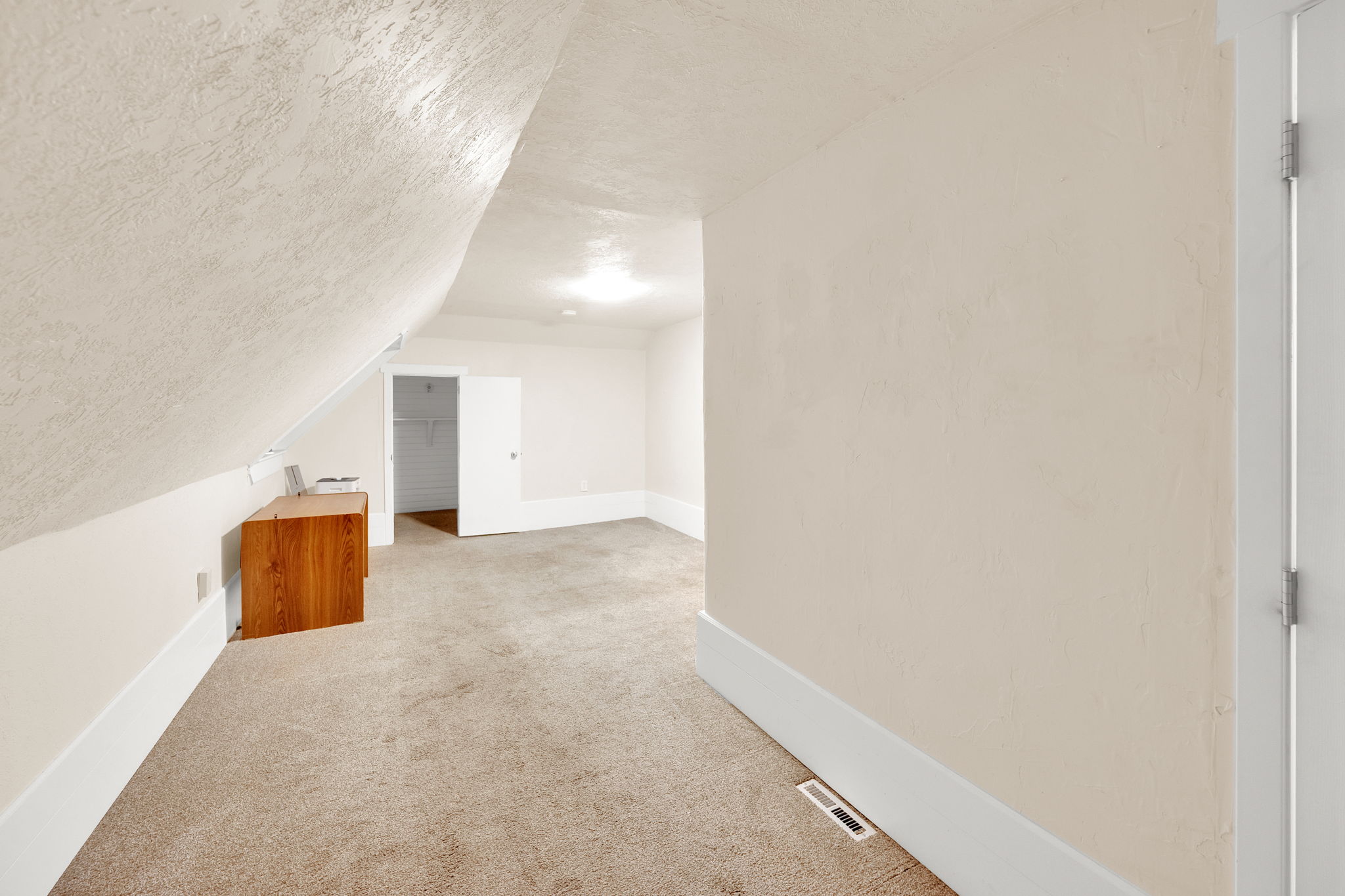 Carpeted room with sloped ceilings, recessed lighting, and a neutral color palette