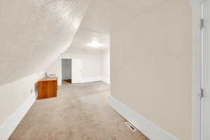 Carpeted room with sloped ceilings, recessed lighting, and a neutral color palette