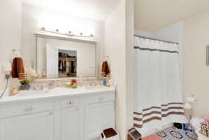 Dual vanity with chrome fixtures and ample counter space, complemented by a large framed mirror with overhead lighting