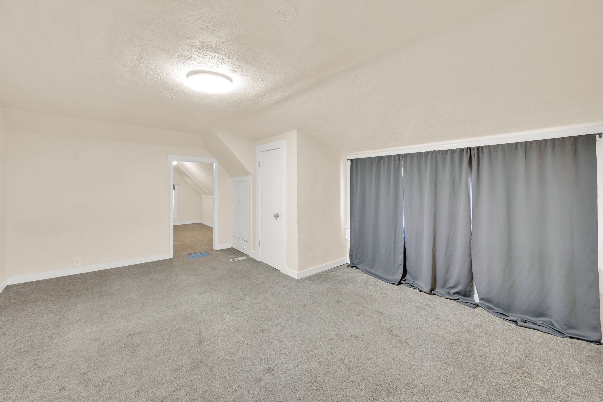 Carpeted room featuring neutral wall tones, a ceiling-mounted light fixture, and a built-in door