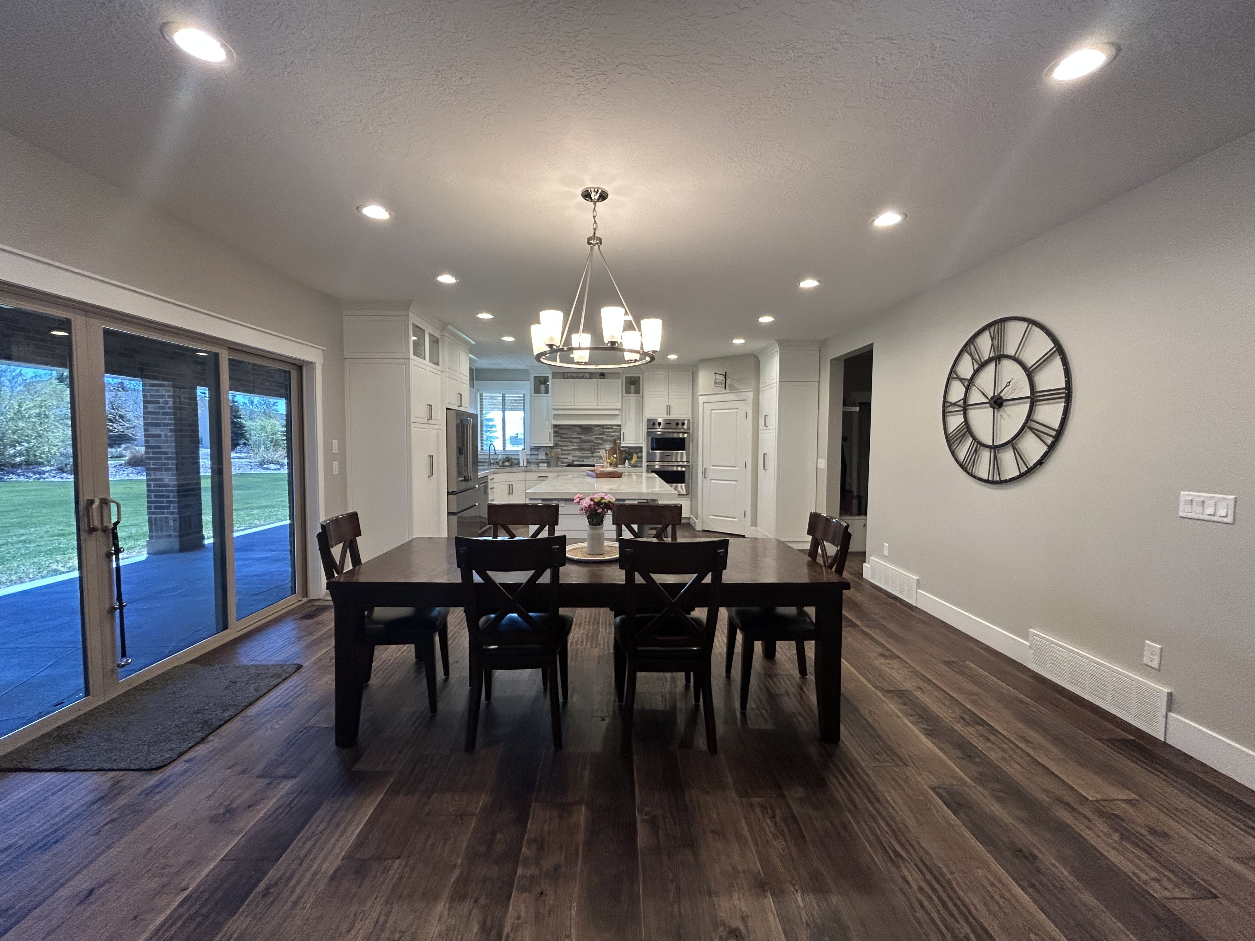 Spacious dining area featuring dark wood-finish flooring, recessed lighting, and a contemporary chandelier