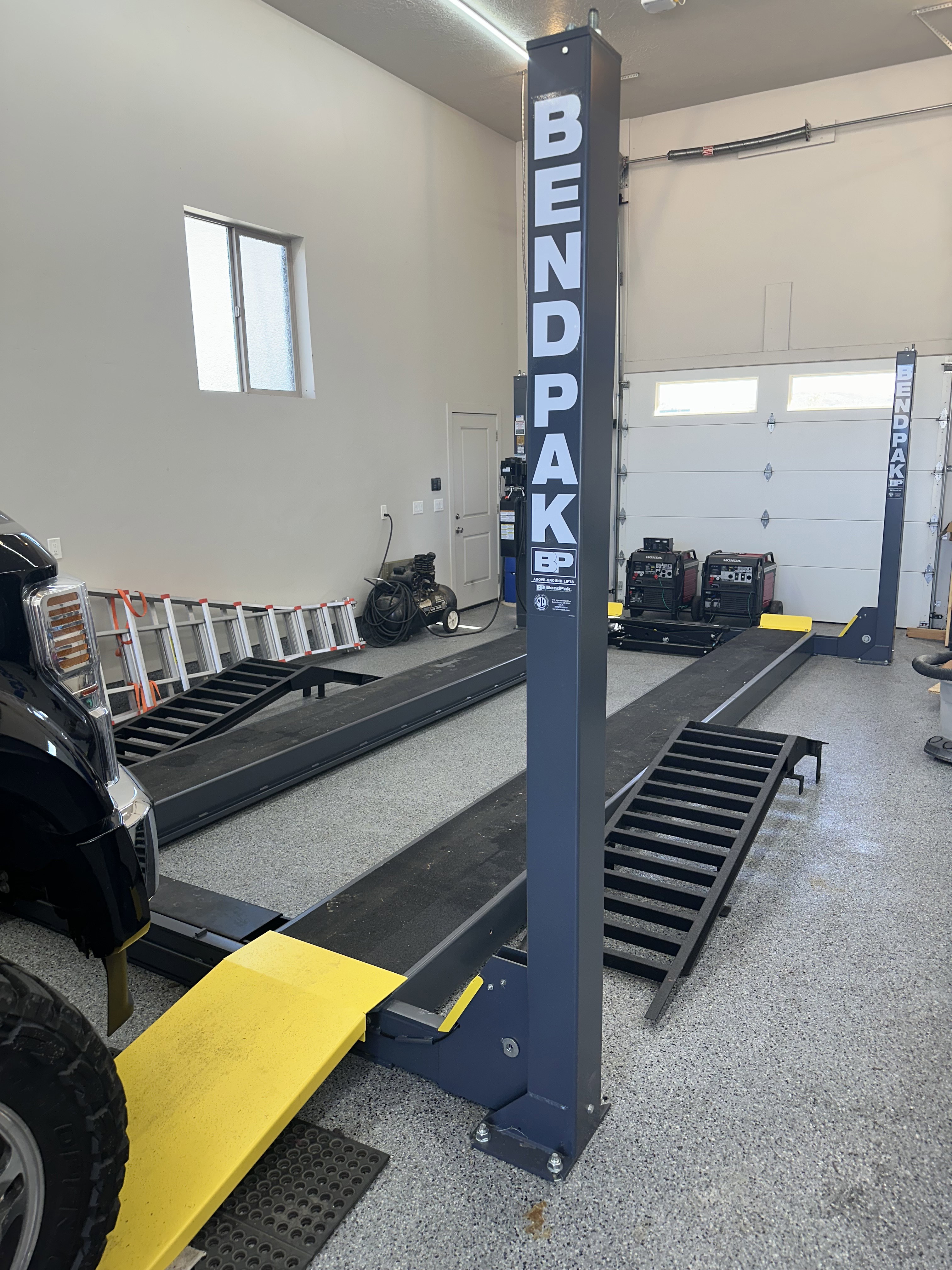 Spacious garage featuring a professional-grade vehicle lift, durable epoxy flooring, and two overhead garage doors