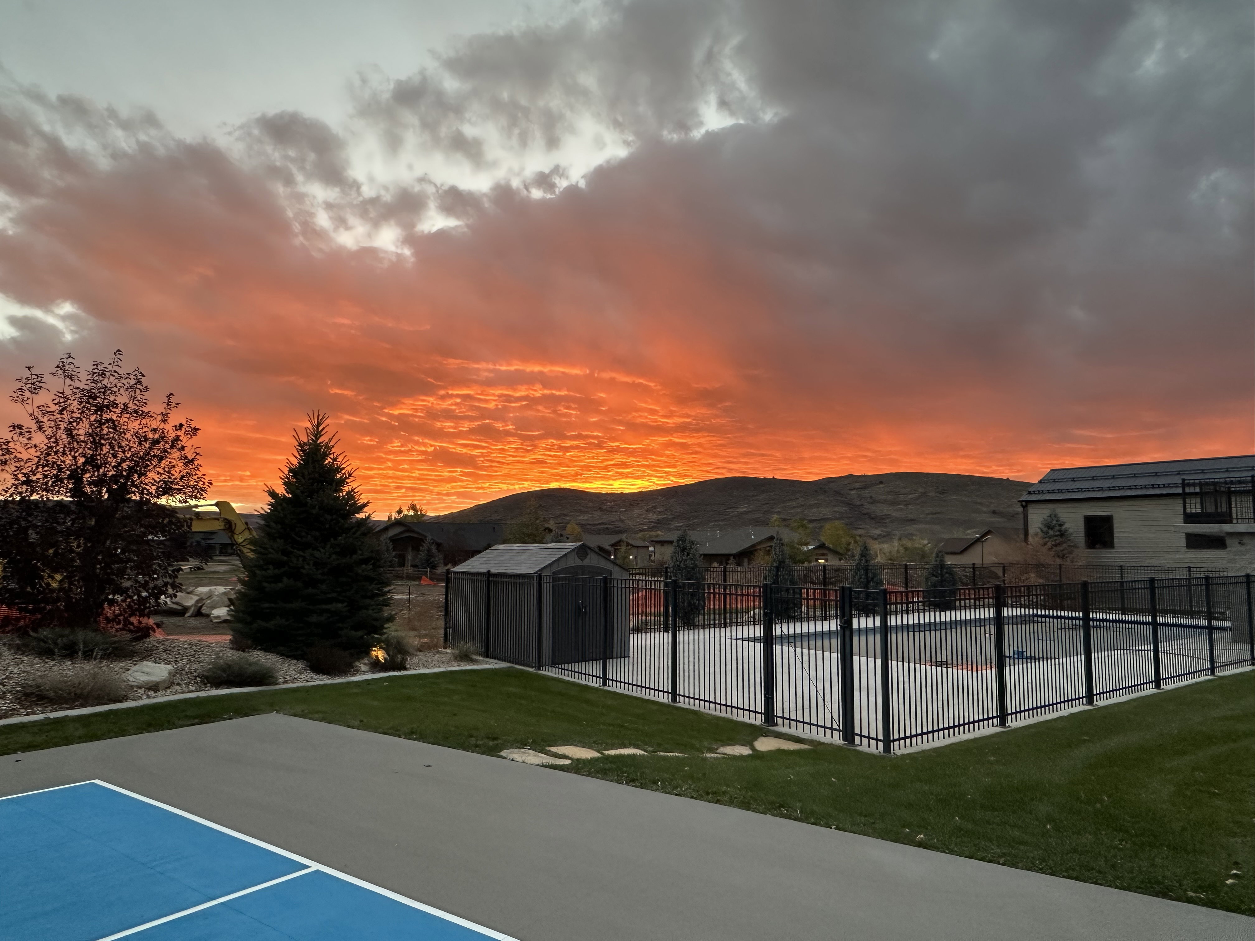 Outdoor recreational amenities featuring a fenced swimming pool, adjacent storage shed, and a hard surface court with blue playing lines