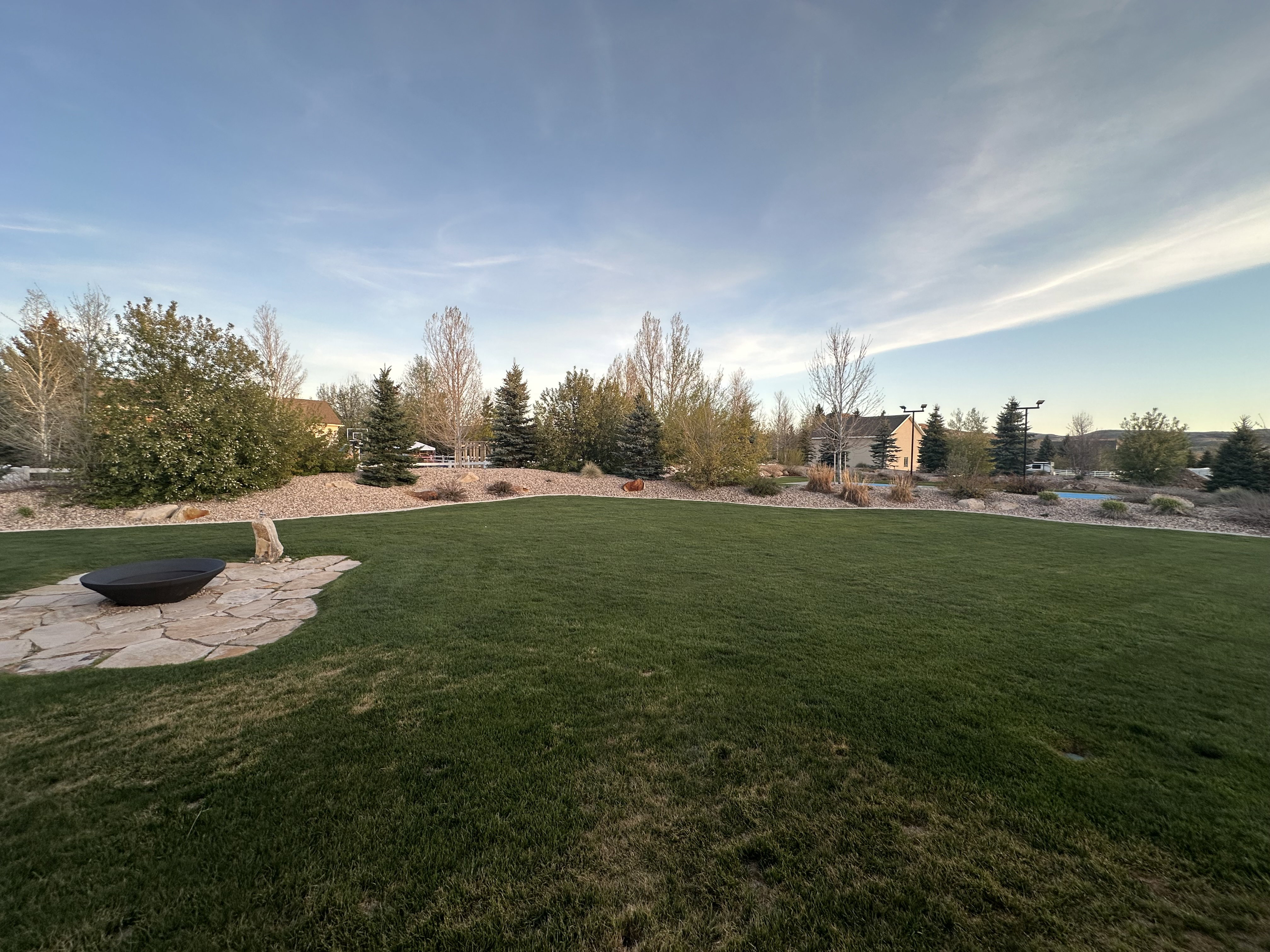 Expansive lawn with a flagstone patio featuring a built-in fire pit