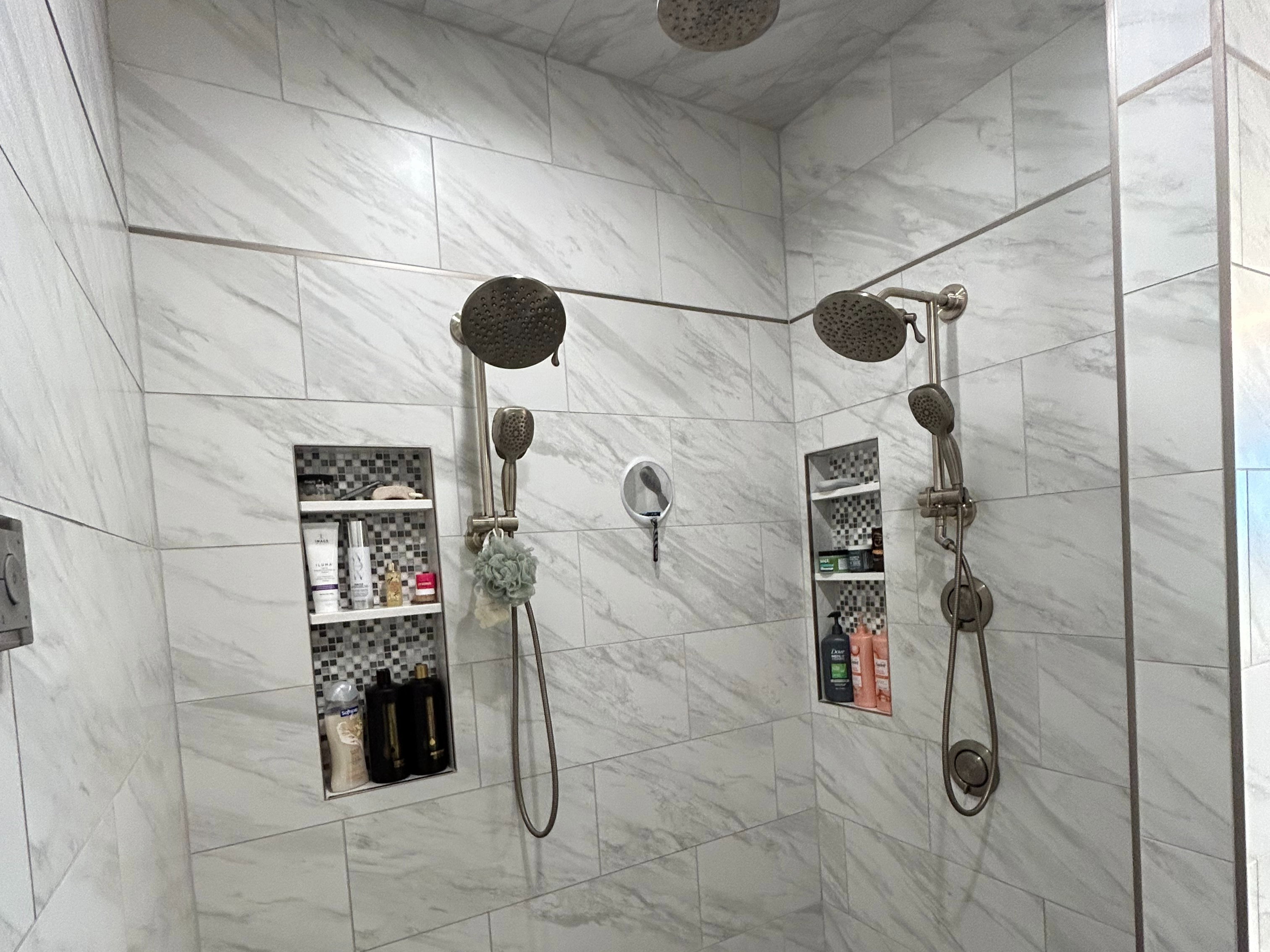 Expansive walk-in shower featuring white marble-look wall tiling and a gray tiled floor