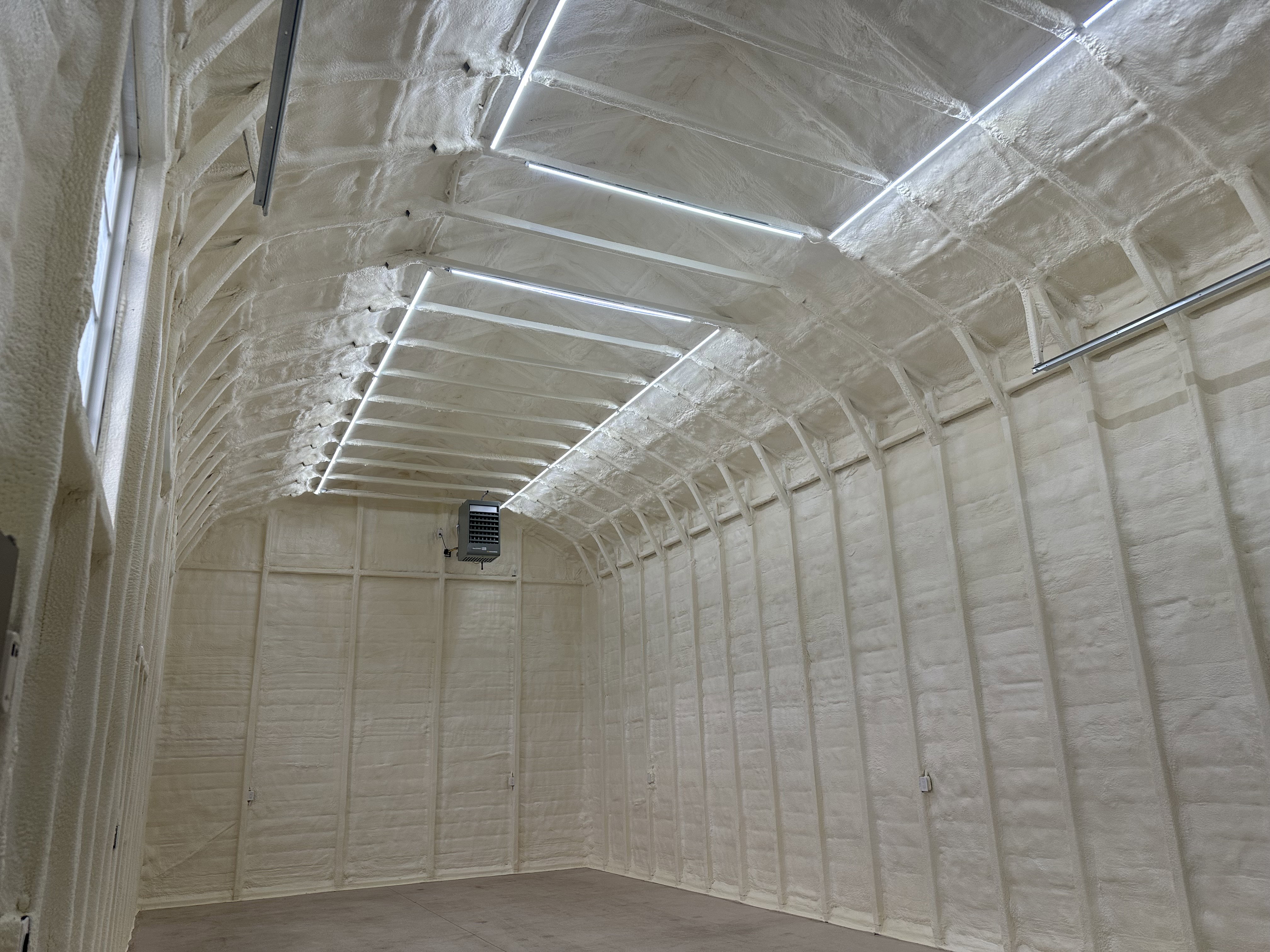 Interior space featuring extensive spray foam insulation on walls and a high arched ceiling