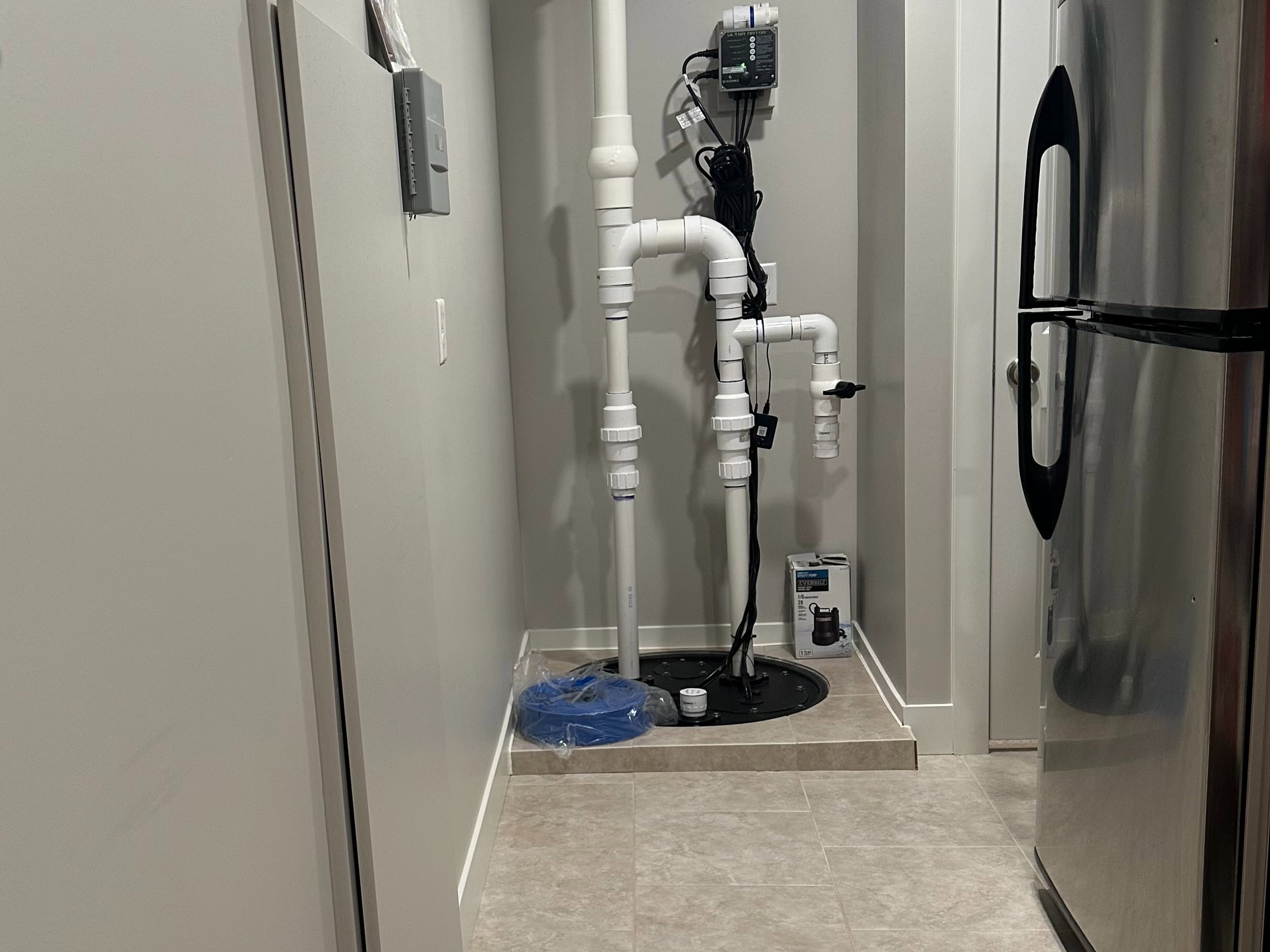 Utility area featuring a sump pump system with PVC piping, recessed lighting, and durable tile flooring