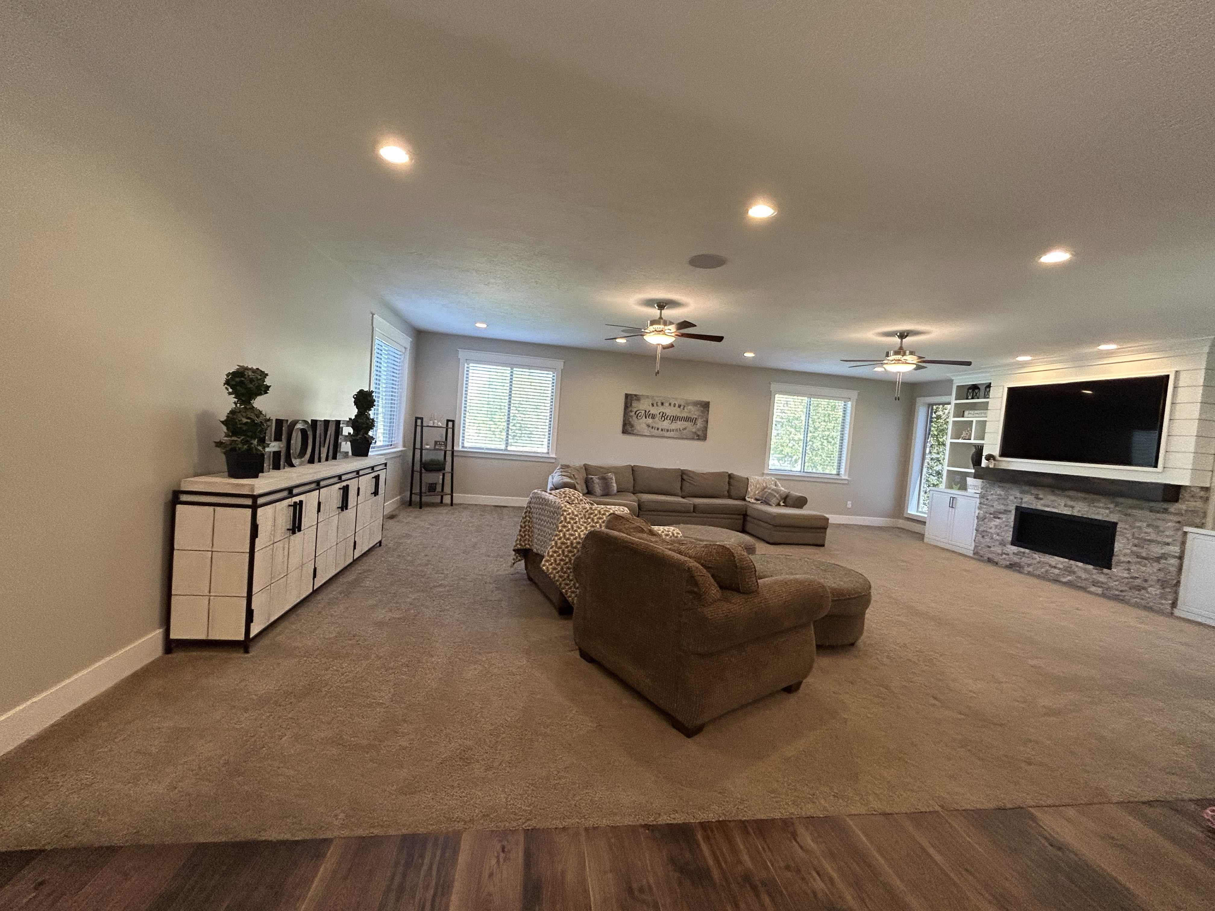Spacious living area featuring neutral carpet and wood-finish flooring, recessed lighting, and ceiling fans