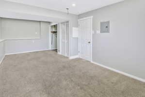 Spacious room with light gray walls, plush carpeting, white trim, and recessed lighting