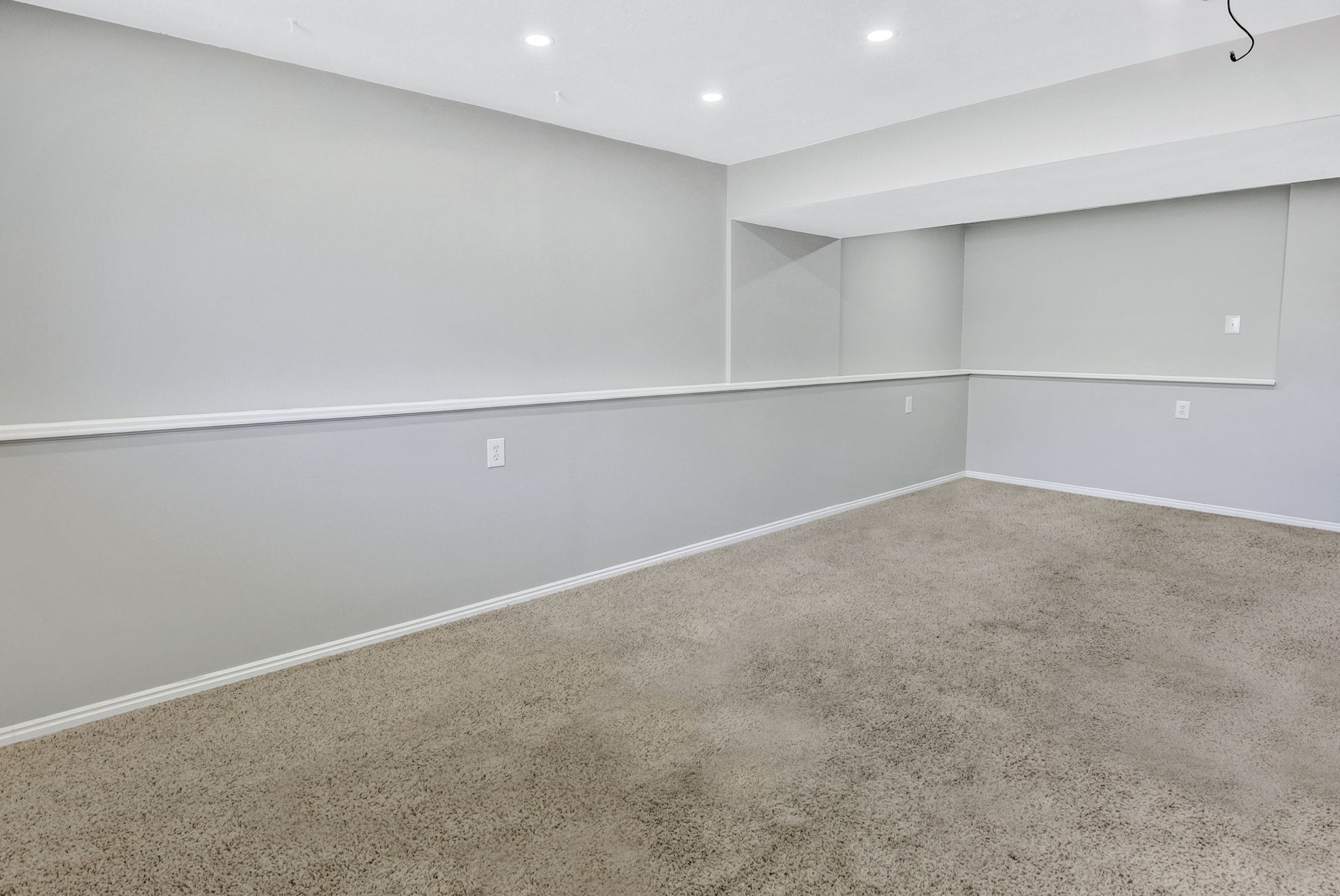 Spacious room featuring neutral carpeting, light gray wall paint, white trim, recessed lighting, and a drop ceiling with integrated lighting