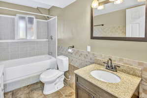 Bathroom featuring a single vanity with a light-toned granite countertop, undermount sink, and a dark-framed mirror