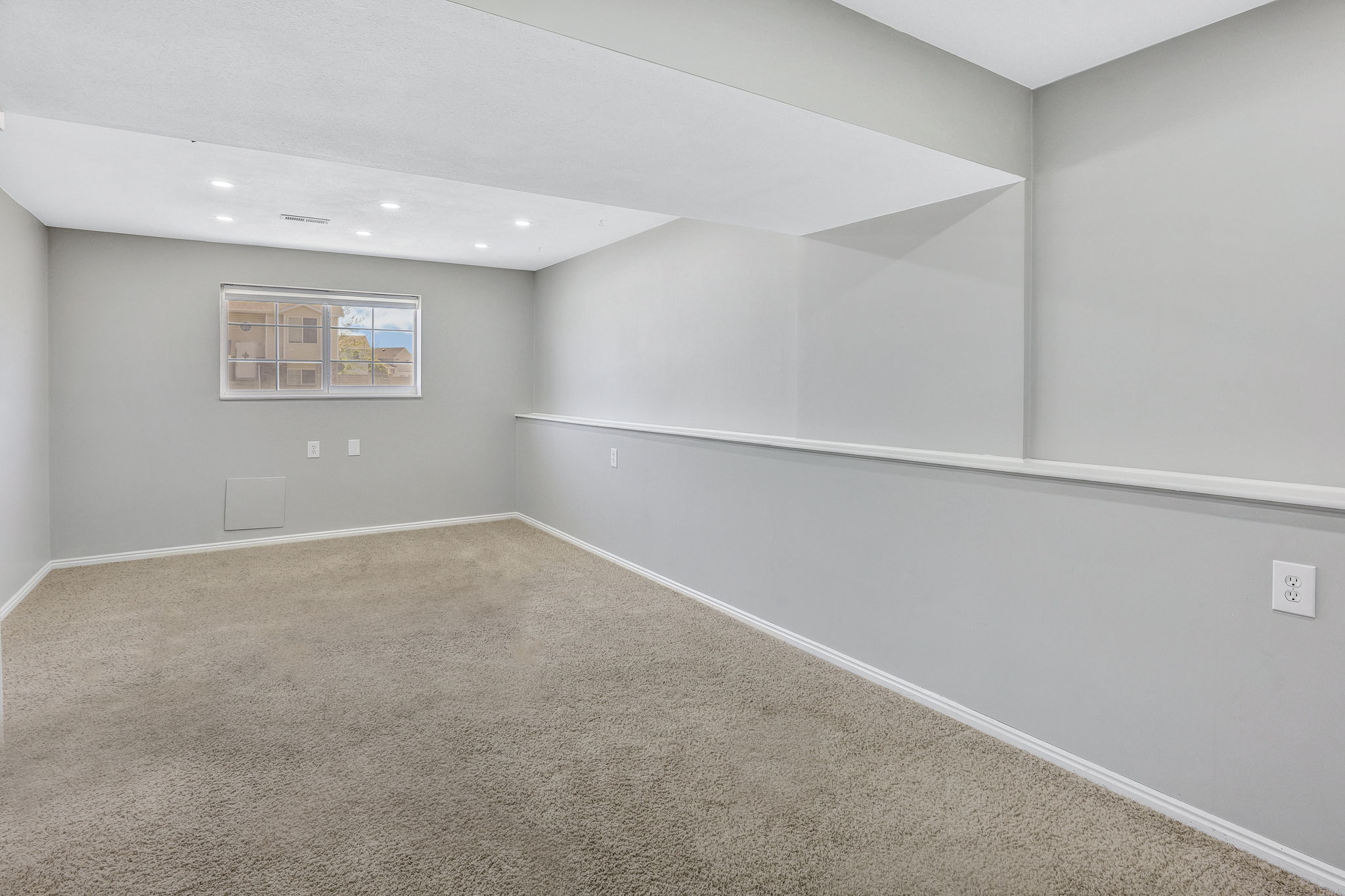 Spacious carpeted room featuring recessed lighting, a window, and light gray walls with white trim